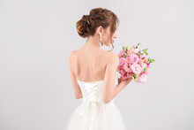 Beautiful Young Bride With Wedding Bouquet On Light Background, Back View