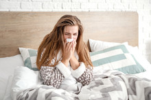 Sick Woman Sitting On Bed At Home