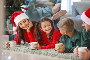 Wall Mural - Happy family drinking hot chocolate at home on Christmas eve