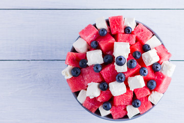 Wall Mural - Watermelon salad with feta cheese in gray bowl. Healthy salad with blueberries, watermelon and soft cheese. Summer salad on white background