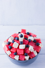 Wall Mural - Watermelon salad with feta cheese in gray bowl. Healthy salad with blueberries, watermelon and soft cheese. Summer salad on white background