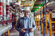 © Dusan Petkovic - Handsome smiling supervisor in gray suit and with white helmet on head holding tablet while looking at camera. Power plant interior.