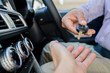 © Nopphon - Businessman giving a car key while sitting in car. Getting new car concept.