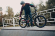 © primipil - Professional young man sportsman cyclist checking pressure in wheel tires him bmx bike at skatepark