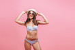 © Smeilov - Girl in swimsuit sunglasses and hat on pink background.
