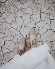 Wall Mural - Overhead vertical shot of a female's feet on a cracked ground