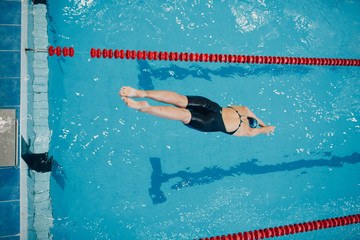 Young woman swimmer jumping in swimming pool