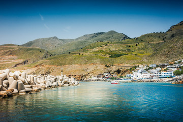 Wall Mural - Waterfront view of harbor on the coastline and mountains in Greek islands, Greece