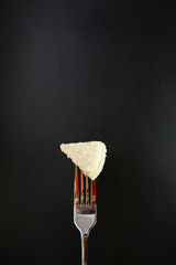 Wall Mural - White cheese on a fork, black background