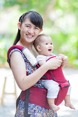 Wall Mural - baby feeling happy and smiles with her mother in the garden.Portrait of Asian family.