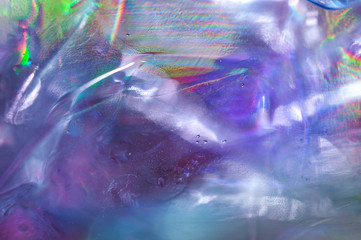 Holographic background in the style of the 80-90s. Real texture of cellophane film in bright acid colors.