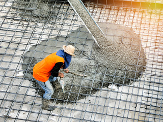 Top view of builders in orange shirt pouring concrete works on the construction site