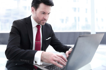 Wall Mural - Businessman typing on a laptop, sitting at his Desk