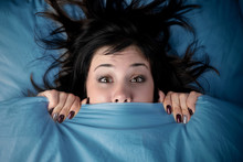Girl Hides Her Face Under The Covers In Bed. A Nightmare After Watching A Horror Movie. Fear Of Nightmares