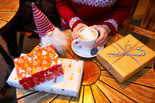 Closeup Of Woman's Hands With Cup Of Coffee And Wrapped Christmas Presents