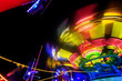 © stefanholm - Abstract colorful funfair carosuell in neon colors in motion at a fun fair