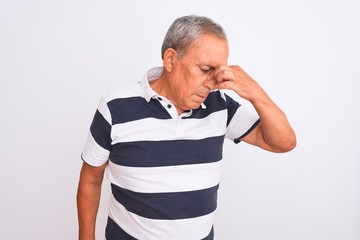 Sticker - Senior grey-haired man wearing casual striped polo standing over isolated white background tired rubbing nose and eyes feeling fatigue and headache. Stress and frustration concept.