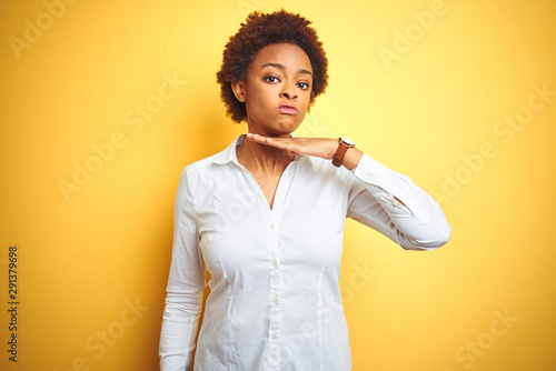 Fotografía African american business woman over isolated yellow background cutting throat w