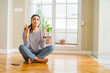 © Krakenimages.com - Young beautiful woman sitting on the floor at home crazy and mad shouting and yelling with aggressive expression and arms raised. Frustration concept.