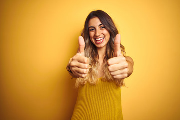 Poster - Young beautiful woman wearing t-shirt over yellow isolated background success sign doing positive gesture with hand, thumbs up smiling and happy. Cheerful expression and winner gesture.