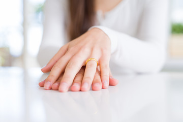 Canvas Print - Close up of woman hands wearing wedding alliance ring over white table