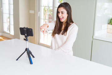 Sticker - Beautiful young woman recording selfie video with smartphone webcam very happy pointing with hand and finger