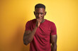 © Krakenimages.com - Young african american man wearing red t-shirt standing over isolated yellow background feeling unwell and coughing as symptom for cold or bronchitis. Healthcare concept.