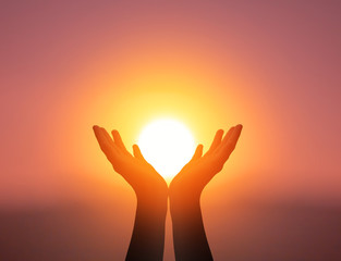 world mental health day concept: silhouette prayer hands in the sunset sky background
