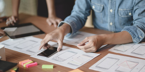 Close-up of UX web developer planing the idea on smartphone application together