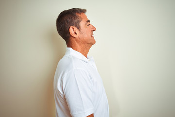 Handsome middle age man wearing polo standing over isolated white background looking to side, relax profile pose with natural face with confident smile.