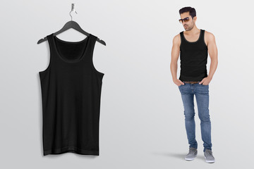 Wall Mural - Hanging black plain tank top shirt on wall along with male model in blue denim jeans pant. Isolated background