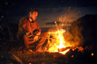 Man sitting next to a bonfire in the dark