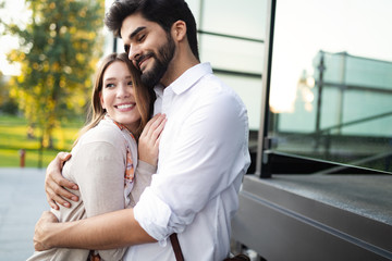 Wall Mural - Happy young couple hugging and laughing outside