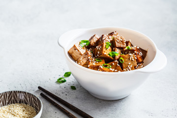 Wall Mural - Teriyaki tofu with sesame seeds and green onion in white bowl. Vegan food concept.