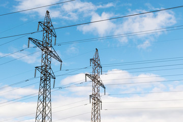 High-voltage technological power lines on metal poles with powerful power wires against the sky