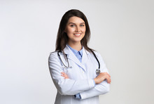 Smiling Female Doctor Standing Crossing Hands Over White Background