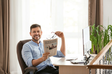 Canvas Print - Man reading newspaper during work in office