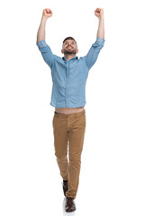 Wall Mural - casual man walking with hands up in the air victorious