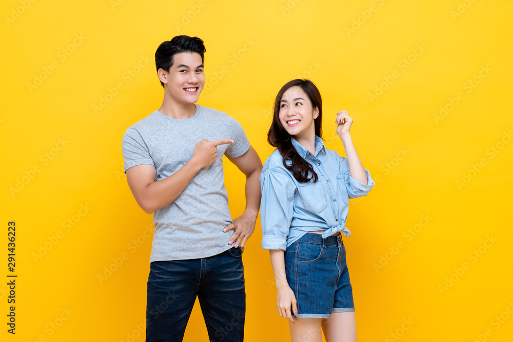 Asian handsome man pointing finger at smiling woman - obrazy, fototapety, plakaty 