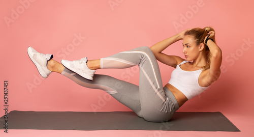 Cuadros en Lienzo Young Woman Doing Bicycle Crunch Exercise, Pink Background, Panorama