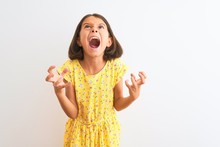 Young Beautiful Child Girl Wearing Yellow Floral Dress Standing Over Isolated White Background Crazy And Mad Shouting And Yelling With Aggressive Expression And Arms Raised. Frustration Concept.