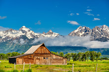 Old Mormon Barn In Grand Teton Mountains With Low Clouds. Grand Teton National Park, Wyoming, USA.