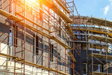 Fototapeta  - Extensive scaffolding providing platforms for work in progress on a new apartment block,Tall building under construction with scaffolds,Construction Site of New Building