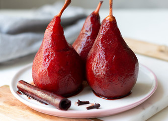 red wine poached pears in white plate, delicious french dessert, close-up