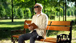 © motortion - Happy blind pensioner reading funny story in braille book, enjoying rest in park