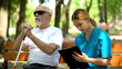 © motortion - Nurse taking notes sitting by blind old patient in park, walking with disabled