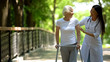 © motortion - Female doctor helping elderly woman with walking frame, hospital park, outdoors