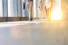 Business People Walking In Office Hall With Yellow Lens Flare In Background