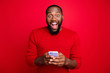 © deagreez - Close-up portrait of his he nice attractive cheerful cheery excited glad bearded guy using wireless connection wi-fi app 5g blog post smm fast speed isolated over bright vivid shine red background