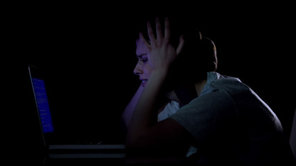 Desperate woman watching at blue screen of death on her laptop, virus attack